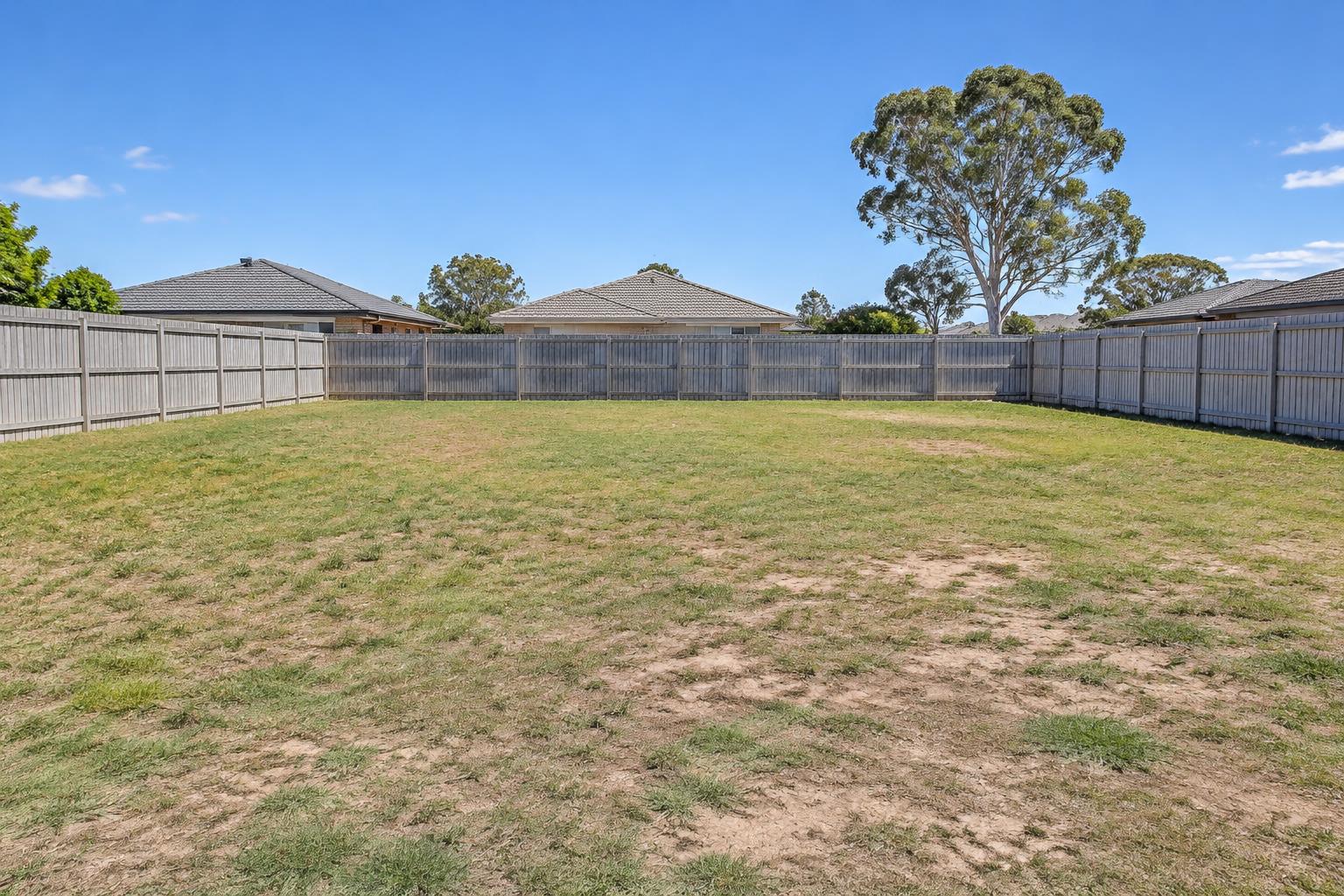 The same backyard before the makeover, with patchy grass and bare dirt